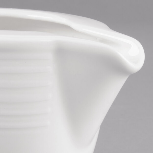 A close up of a Villeroy & Boch white porcelain creamer with a handle.