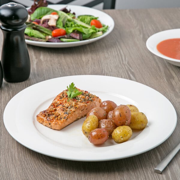 A close-up of a white Villeroy & Boch porcelain plate with a piece of salmon and a leafy garnish on top.