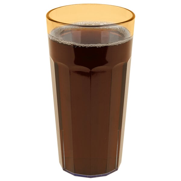 A Cambro Newport amber plastic tumbler filled with dark liquid with a yellow rim.
