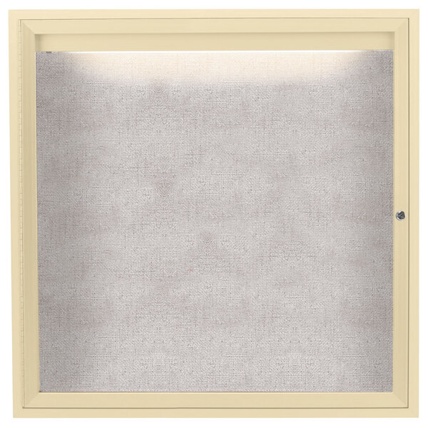 An ivory enclosed bulletin board with a light inside.
