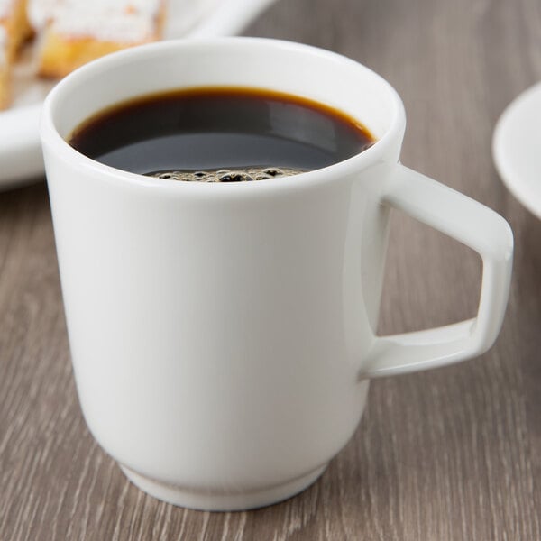 A Villeroy & Boch white porcelain mug filled with coffee on a table.