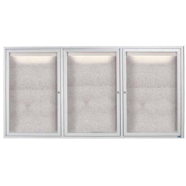 A white Aarco outdoor bulletin board cabinet with three glass doors and lights.