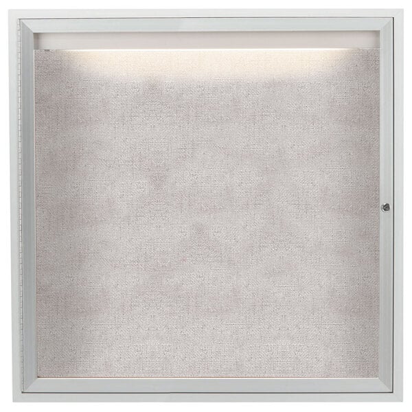 A white framed Aarco bulletin board with a light on it.