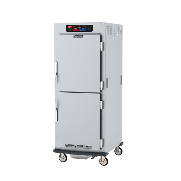 A stainless steel Metro C5 heated holding and proofing cabinet on wheels with solid dutch doors.