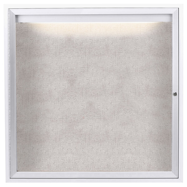 A white square enclosed bulletin board with a light on it.