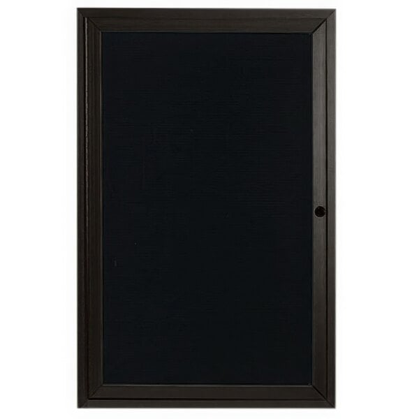 A black rectangular message center with a black frame on a black door.