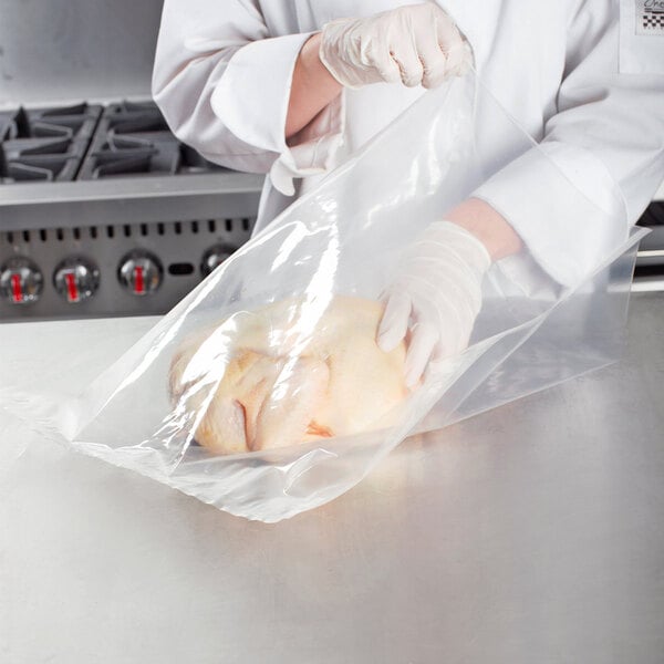 A person in a white coat putting a VacPak-It plastic bag on a chicken.