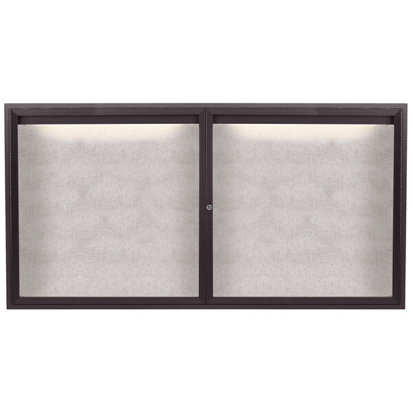 An Aarco bronze anodized enclosed bulletin board with two doors.