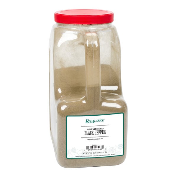 A plastic container of Regal Fine Grind Ground Black Pepper with brown powder inside.