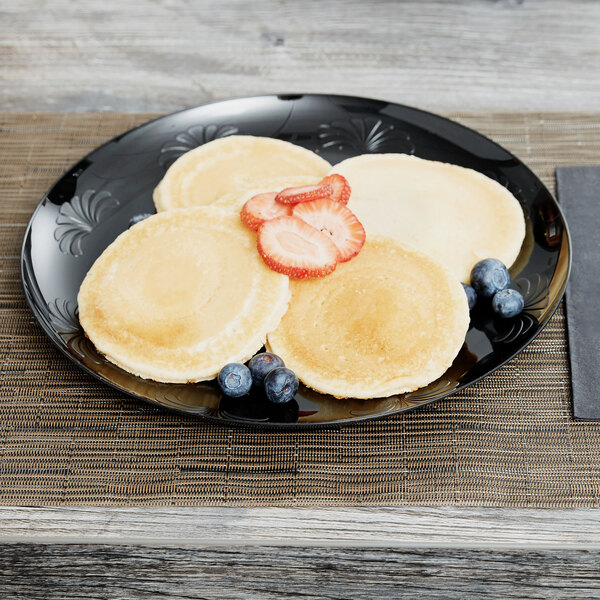 A WNA Comet black plastic plate with pancakes, strawberries, and blueberries.