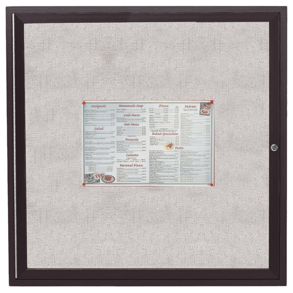 An Aarco bronze anodized bulletin board cabinet with a brown frame holding a menu with a price list.