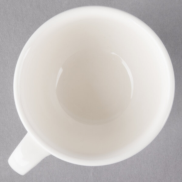 A Villeroy & Boch white porcelain cup with a handle on a gray surface.
