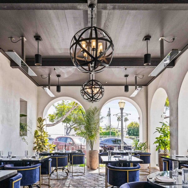 A black electric outdoor patio heater mounted on the ceiling of a restaurant patio.