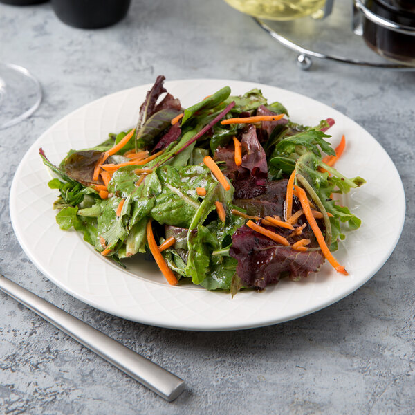 A Villeroy & Boch white porcelain plate with a salad of carrots and greens on it.
