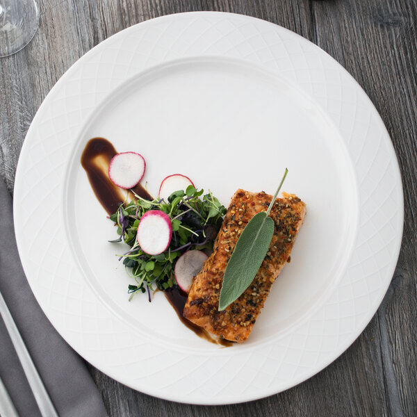 A Villeroy & Boch white porcelain round platter with fish and salad on it.