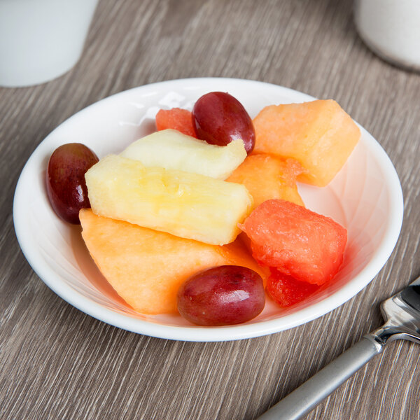 A Villeroy & Boch white porcelain bowl filled with grapes and melon on a table.