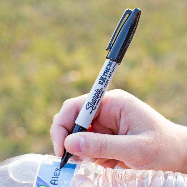 A hand holding a Sharpie Extreme Black Fine Point marker.