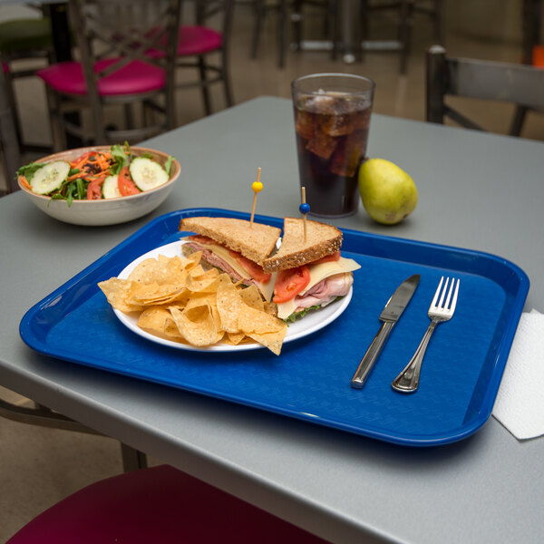 A Carlisle blue plastic fast food tray with a sandwich and chips on it.