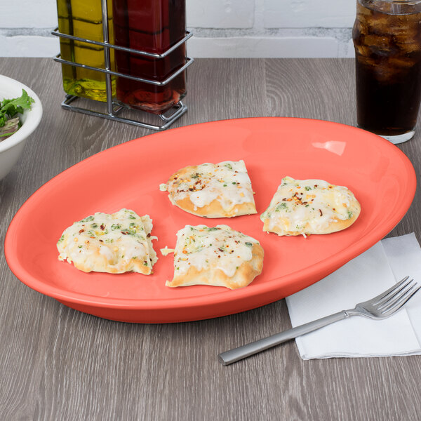 A Tuxton Cinnebar oval china platter with four slices of pizza on it.