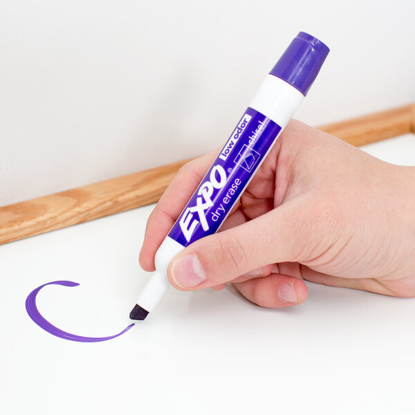 A hand holding a purple Expo dry erase marker.
