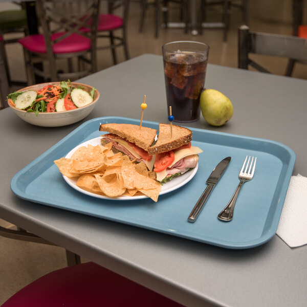 A Carlisle fast food tray with a sandwich, chips, and a drink on it.