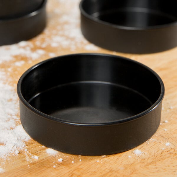A black Matfer Bourgeat tartlet / mini cake pan on a table.