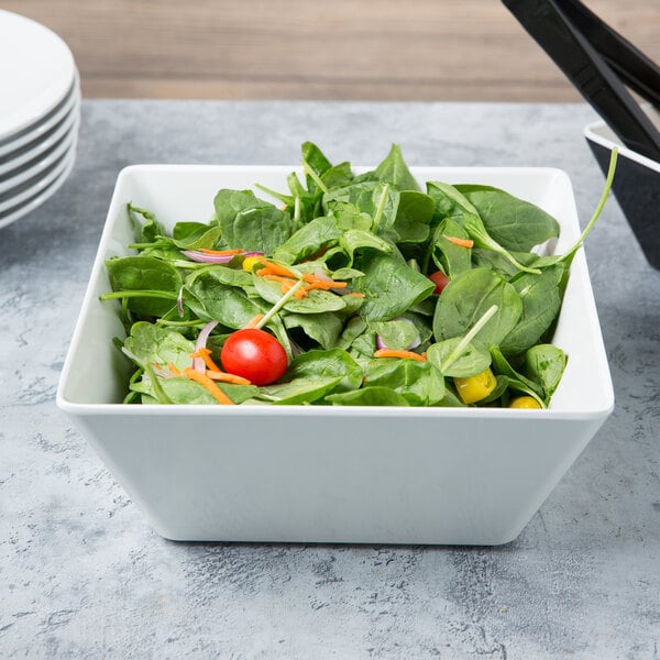 A white Vollrath melamine bowl filled with salad with tomatoes and carrots.