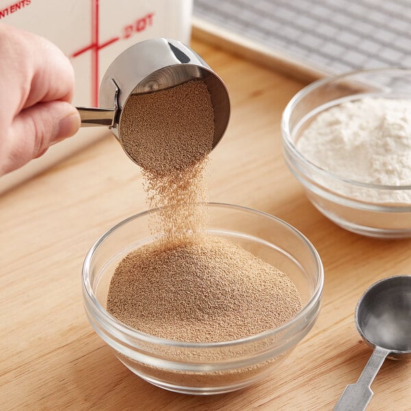 A person pouring brown Lesaffre Red Star Bakers yeast into a bowl.