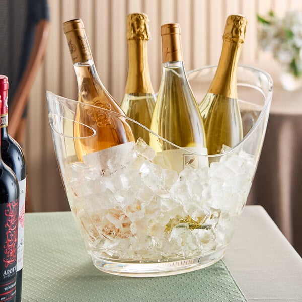 A large clear acrylic oval wine bucket holding four wine bottles in ice.