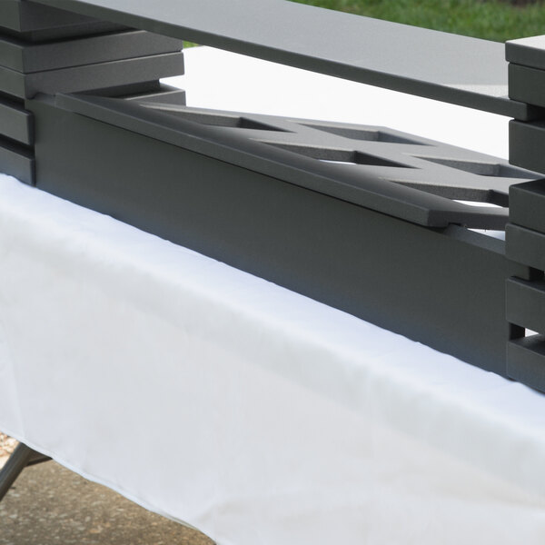 A black wood long display riser on a table with a white table cloth.