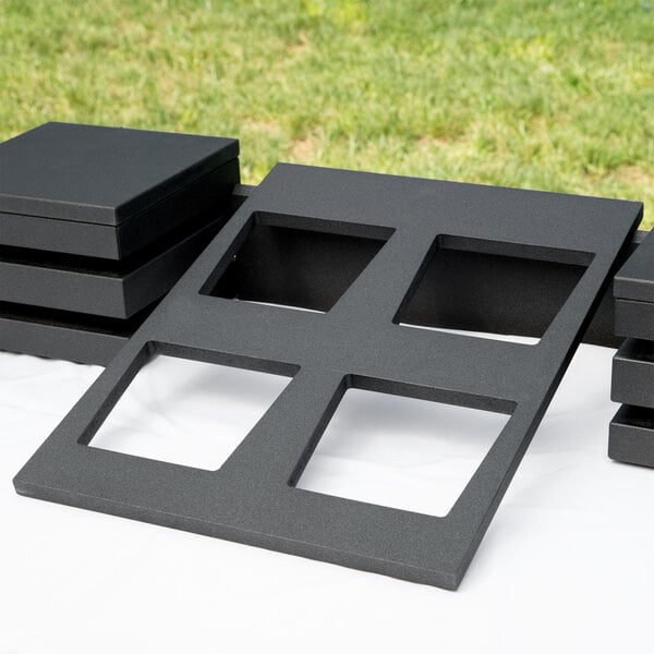 A Vollrath black wood display template with four square openings.