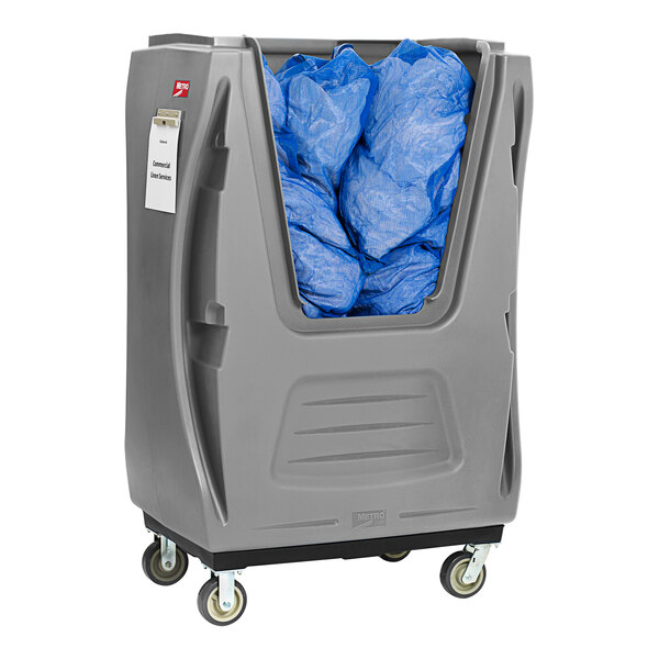 A grey plastic MetroTrux laundry container with blue bags inside.