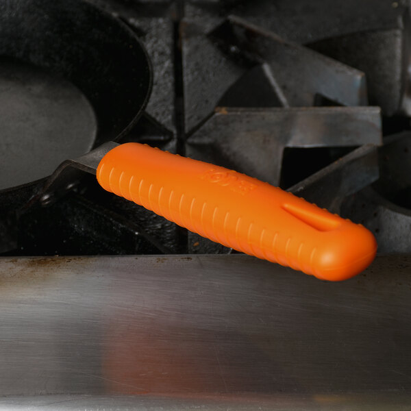 An orange silicone handle holder on a Lodge carbon steel skillet.