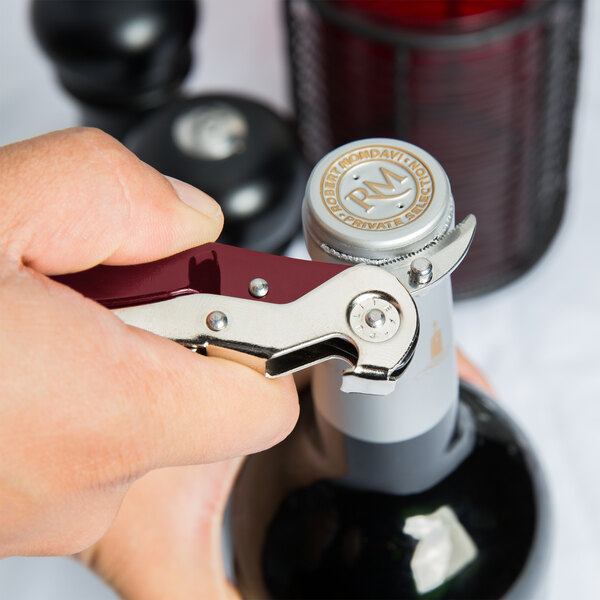 A hand using a Pullparrot waiter's corkscrew to open a bottle of wine.