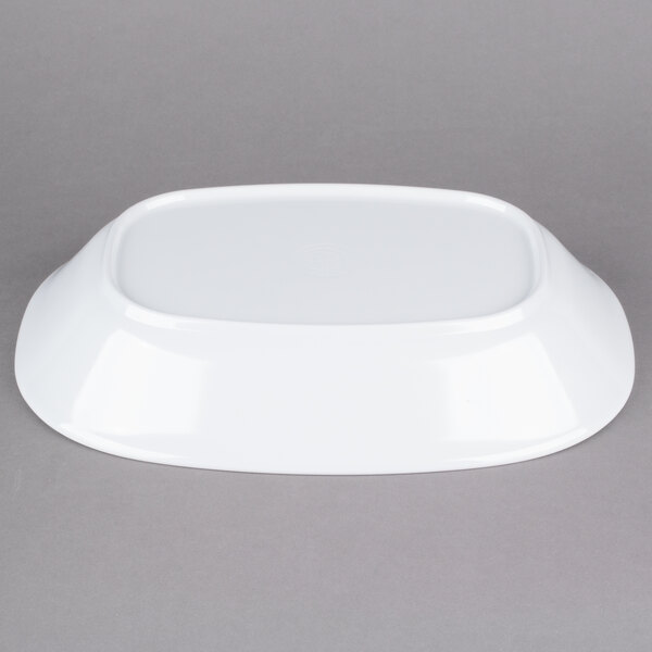An oblong white melamine bowl on a gray surface.