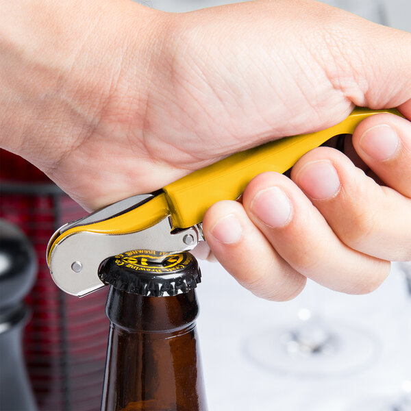 A person using a yellow Pulltap's Original Waiter's Corkscrew to open a bottle on a counter.