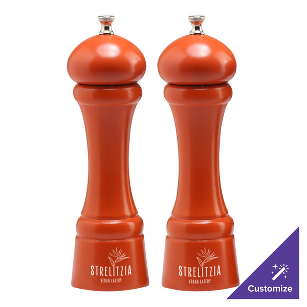 Two orange Chef Specialties pepper mills on a table.