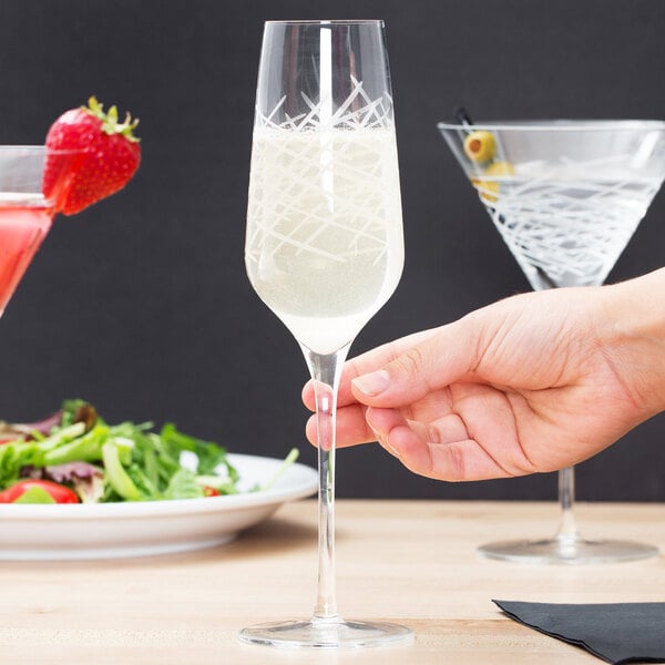 A person holding a Reserve by Libbey Crosshatch Champagne Flute filled with champagne.