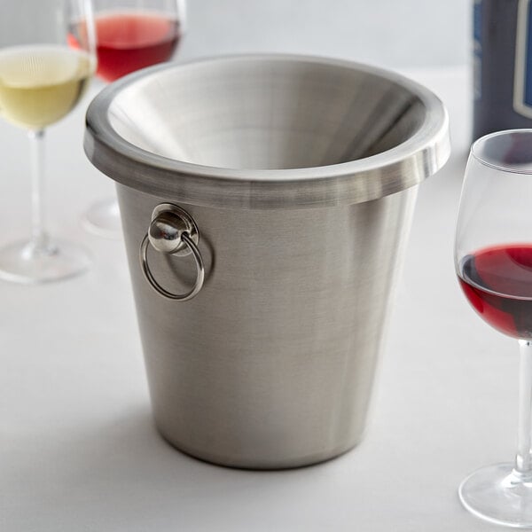 A silver wine spittoon with a glass or red wine, white wine, and a rose wine next to it 