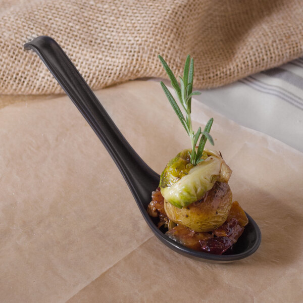 A black matte Nara melamine soup spoon with food on it.
