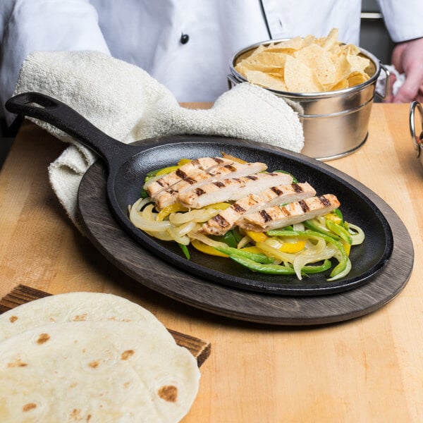 A chef prepares a meal on a Lodge cast iron fajita skillet on a table.