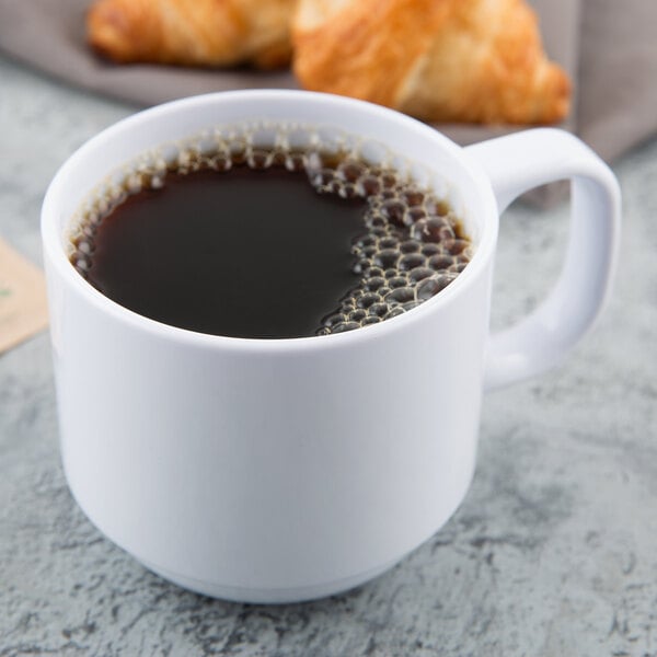 A white GET Tritan mug of coffee with a croissant on the table.