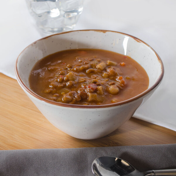 A Rustic Mill melamine bowl filled with soup on a table.