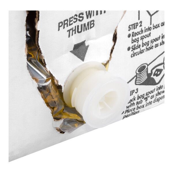 A close-up of a white plastic spout protruding from a torn section of a cardboard box with printed instructions.