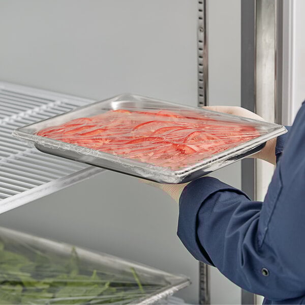 A person holding a Vollrath stainless steel tray of food.