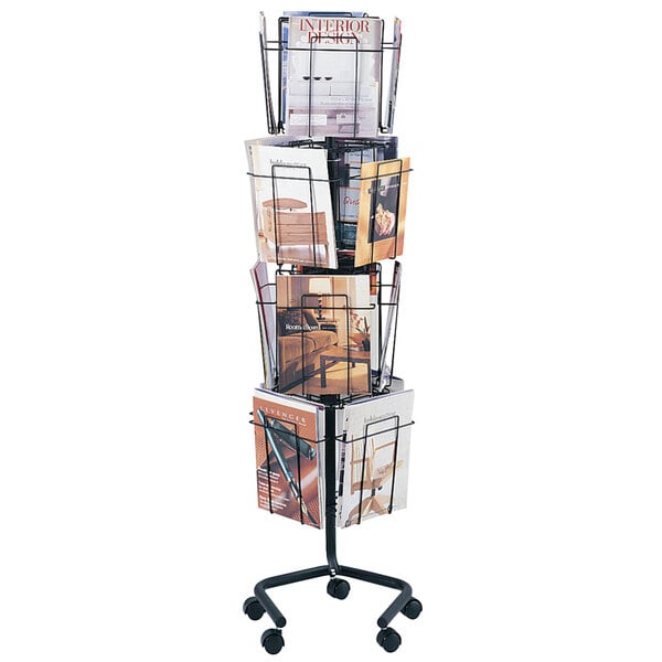 A Safco charcoal metal rotary wire magazine rack with magazines on it.