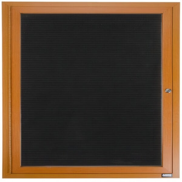 An outdoor black vinyl letter board with a wooden frame and black glass doors with a brown border.