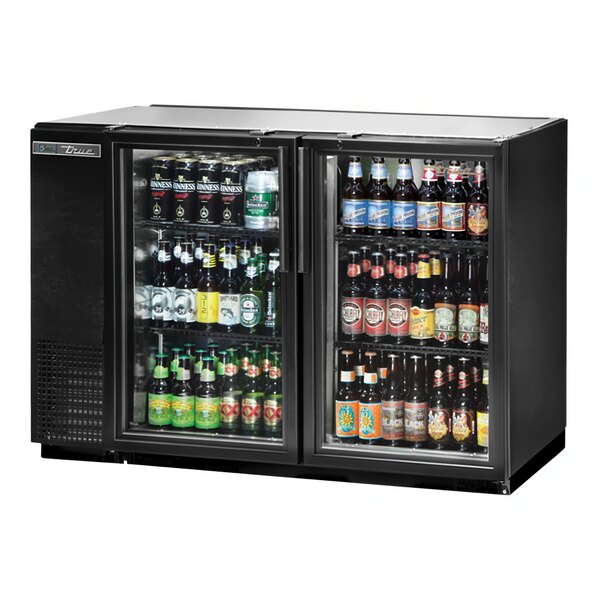 A True black glass door back bar refrigerator with bottles of beer inside.