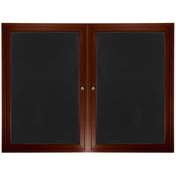 An Aarco walnut outdoor directory board with black vinyl letter board behind black glass doors.