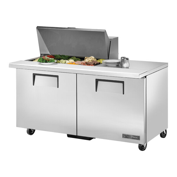 A True refrigerated sandwich prep table with large salad bowls on a counter.